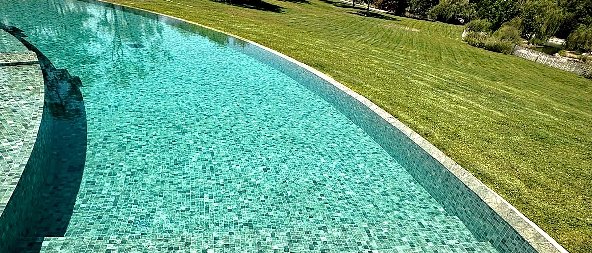 Grand parc engazonné bordant une piscine en mosaïque